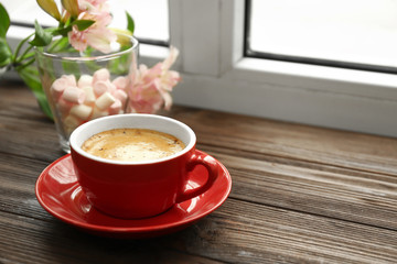 Cup of coffee, marshmallow and flowers on window sill