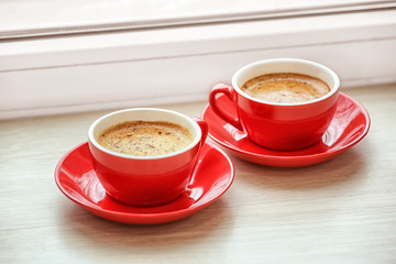 Cups with hot coffee on window sill
