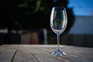 Close up image of wine being poured into a glass on a wooden table outside with natural light