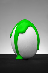 White easter  egg with liquid color splash on the grey background