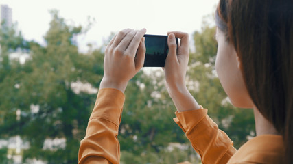 a woman holding a phone, photographing nature