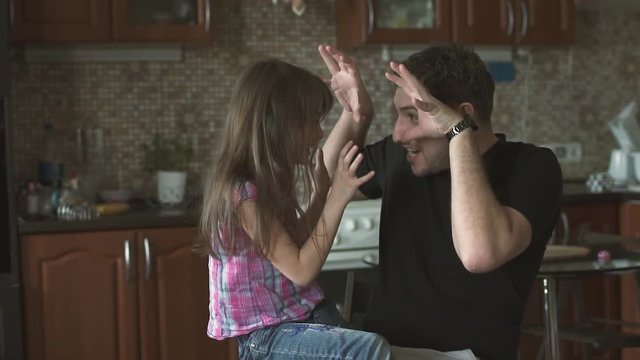 Father and little daughter are fooling around, playing and having fun in the kitchen. slow motion