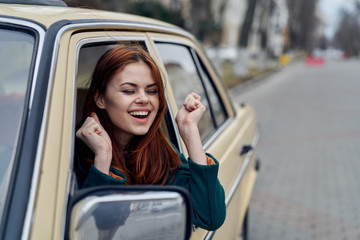 Fototapeta na wymiar cheerful woman peeking out of car window, driver