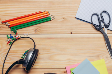 color pencils headphones and scissors with notebooks on a wooden table