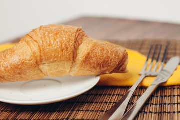 croissants and yellow napkin, fork and knife