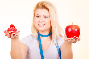 Woman choosing between apple and sweet cupcake