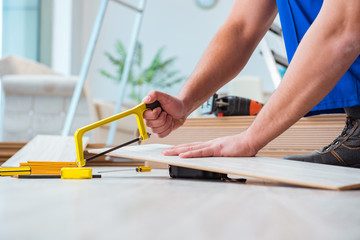 Naklejka premium Repairman laying laminate flooring at home