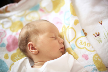newborn baby sleeping in the crib on a blanket.