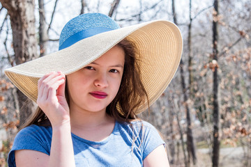 A young girl with straw hat is enjoying a sunny day at springtime