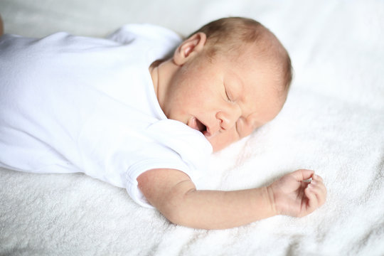 cute newborn baby sleeping peacefully on white blanket