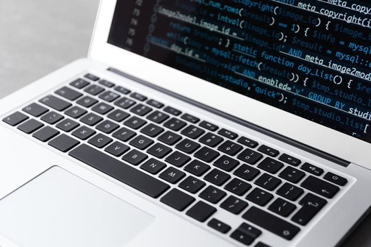 Laptop of programmer with script code on display