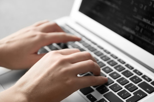 Programmer using laptop, closeup