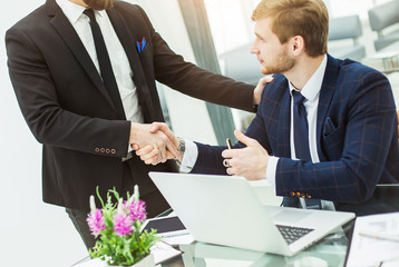handshake between colleagues in the workplace in a modern office
