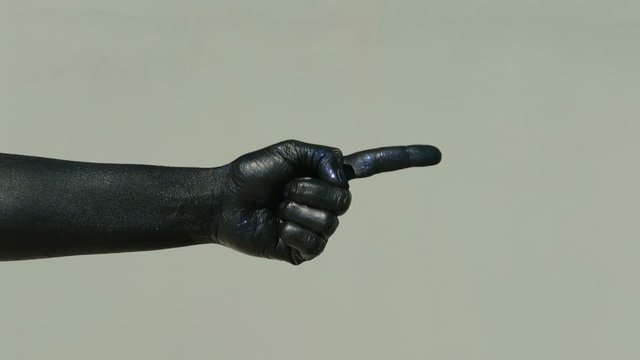A black hand on a light wall shows a pantomime with an index finger. Finite man in a shiny soot indicates the direction of movement and rocking. A dark palm with a blue tint depicts a figure for the