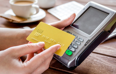 Payment by card in cafe with terminal and keyboard on wooden background