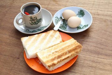 Breakfast set of half boiled eggs, toast and coffee, popular meal in Malaysian and Singaporean coffeeshops