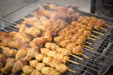 Roasting chicken, grilled spiced chicken stab in wood on a grate.