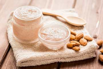 body scrub with almonds for body care on wooden table background