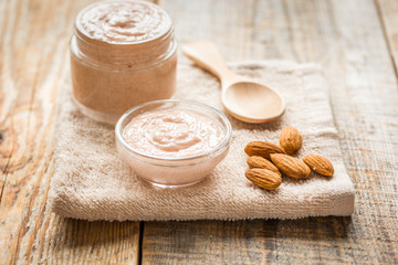 cosmetic set with almond scrub on table background