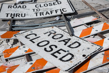 Road Closed Signs fell down on a road with broken barricades like a dump close to construction zone. Miami. Florida. USA