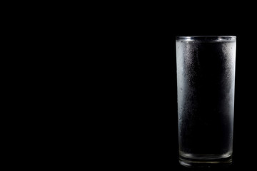 Glass with cold water on black background