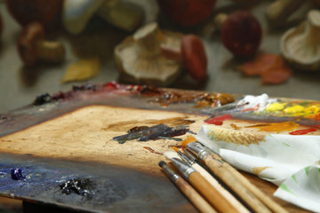 The workplace of the artist, brushes, paints and canvas. Multicolor oil paints on a palette close up.