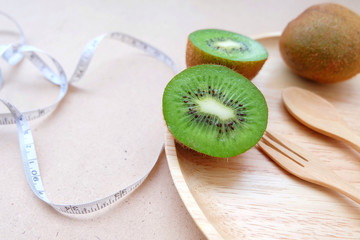 Tape measure and fresh kiwi fruits on wooden background. Weight loss and detox concept. Top view and copy space
