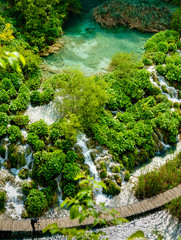 Pool and waterfalls through greenery covered rocks and walkway Plitvice Lakes National Park and World Heritage site, Croatia.