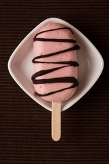 Eis am Stiel mit Erdbeereis und Schokolade als Glasur