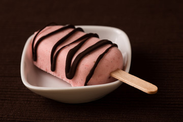 Eis am Stiel mit Erdbeereis und Schokolade als Glasur