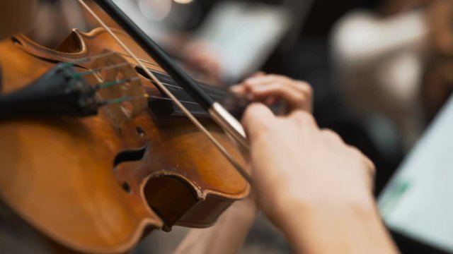 Women performs lead violin sole part playing at classical concert. Professional symphonic orchestra musicians at rehearsal, accompanying opera singer at theatre. Audience enjoying music, inner harmony