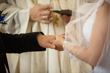 Bride putting a ring on groom's finger during wedding ceremony