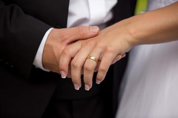 Groom holding bride's hand with wedding or engagement ring