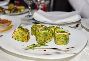 Green roll with spinach, salmon and cream cheese. Slices on a white plate
