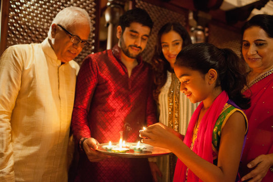 Family decorating with oil lamps on diwali.