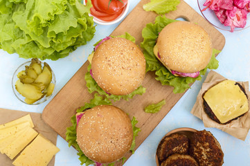 Hamburgers with juicy cutlet, tomatoes, pickled cabbage and cucumbers, cheese, green lettuce leaves and a soft bun with sesame