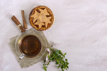 Sweet apricot cake - tartlet of pastry filled with jam and a cup of tea with cinnamon. Top view.