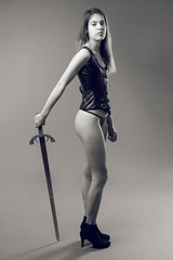 Attractive girl poses with leather corset and medieval sword