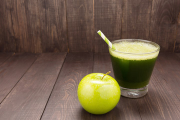 Healthy green smoothie with apple on rustic wood background.