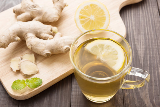 Cup of ginger tea with lemon on wooden background