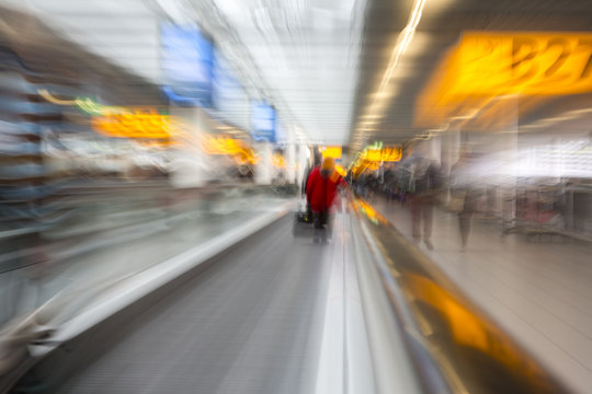 Rushing through the airport terminal to catch the next layover flight. Motion blurry image on an escalator. Last minute hurry to not to be late to the gate and miss the flight.