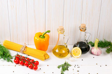Spaghetti, tomatoes cherry, olive oil, herb and spices on old white wooden background. Set for healthy foods. Ingredients for salad