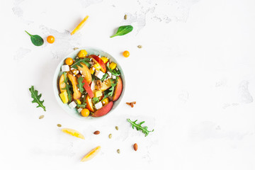 Peach salad. Spinach leaves, arugula, sliced peaches, mango, nuts, feta cheese on white background. Healthy food concept. Fat lay, top view