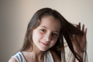 smiling little girl straightens her hair with one hand