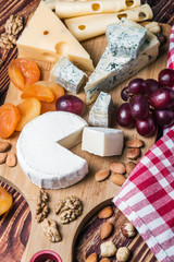 Assorted cheeses with grapes and nuts on a wooden table