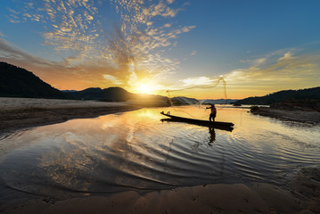 Silluate fisherman and boat in river on during sunrset,Thailand