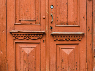 Fototapeta premium Old red-orange wooden door with carved vintage elements