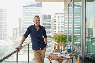 Expat man standing at balcony.