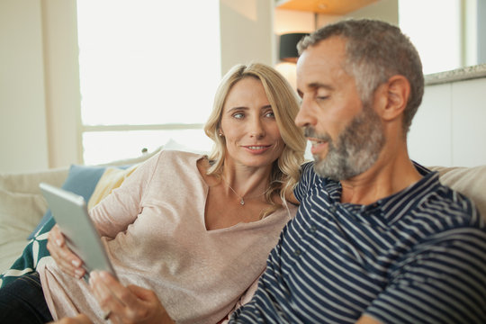 Couple using digital tablet at home.