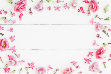 Flowers composition. Frame made of various pink flowers on wooden white background. Flat lay, top view